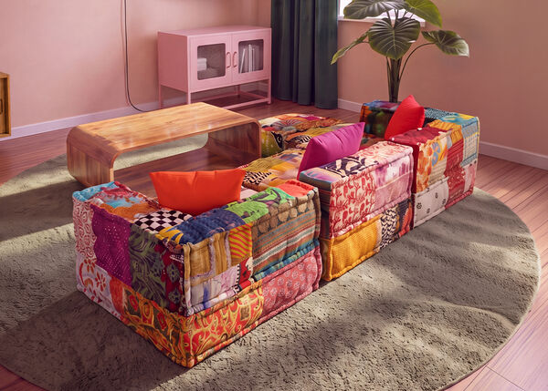 Canap&eacute; modulable patchwork color&eacute; dispos&eacute; autour d&rsquo;une table basse en bois sur un tapis rond, dans un salon contemporain.