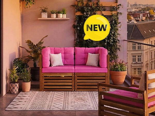 Nouveau canap&eacute; modulaire de balcon avec des coussins roses vifs et une structure en bois massif, am&eacute;nag&eacute; sur un balcon urbain avec des plantes et une rambarde en verre, badge NEW affich&eacute;