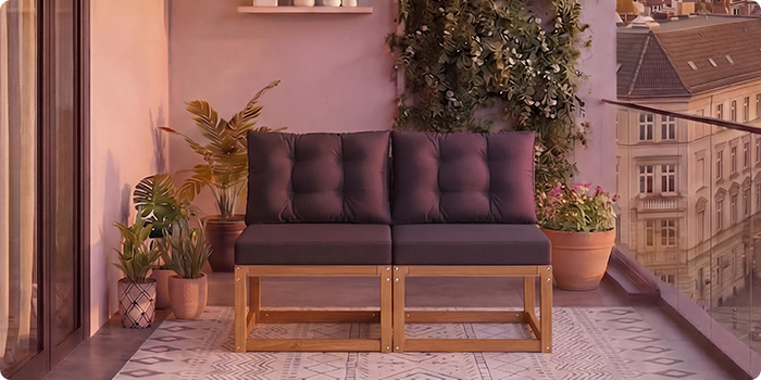 Canapé modulaire en bois deux places avec des coussins gris foncé sur un balcon entouré de plantes en pot et une vue sur la ville en arrière-plan