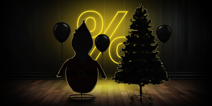  Figurine gonflable du Père Noël et sapin de Noël avec des ballons noirs devant un panneau de pourcentage jaune vif sur un plancher en bois sombre.