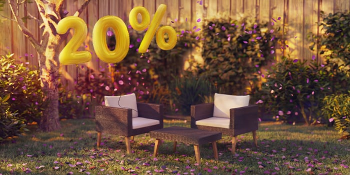Fauteuils lounge d’extérieur en rotin avec coussins et une petite table dans un cadre de jardin, décorés de confettis roses et de ballons dorés « 20 % de réduction », mettant en avant des offres saisonnières sur les meubles lounge de jardin.